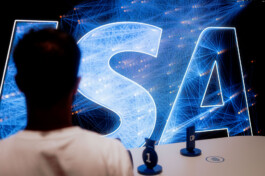 A person looks at a large digital visualization with glowing network lines and the word 